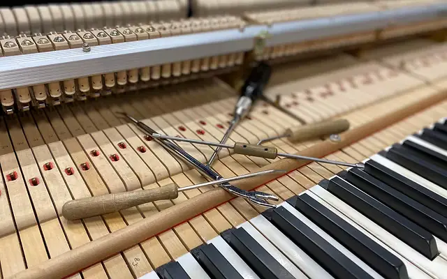 Blick ins Klavierinnere mit Stimmwerkzeug auf dem Resonanzboden aus Holz